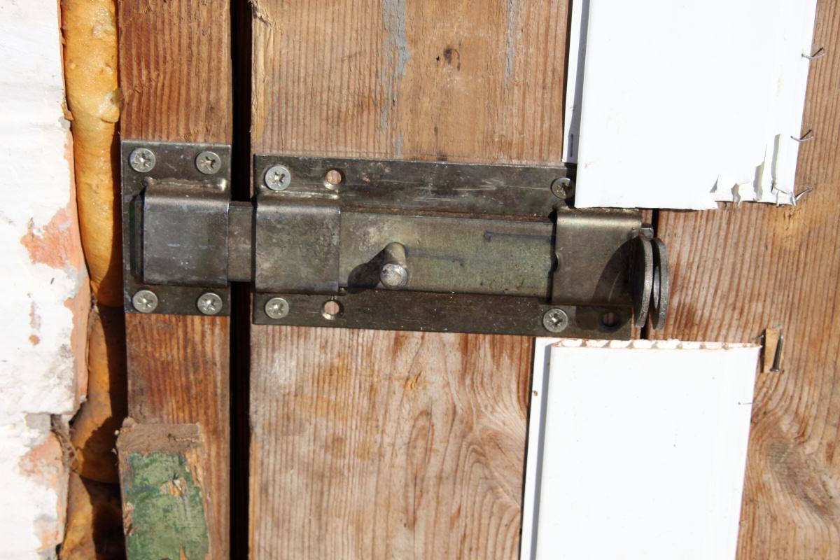 Задвижка металлическая на деревянной двери сарая
